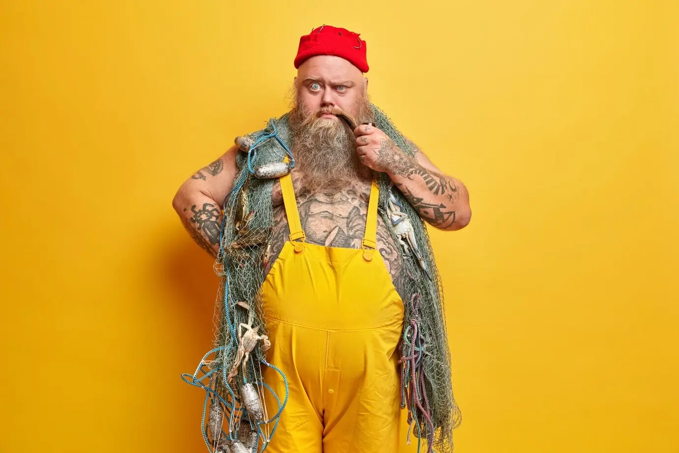 Fettleibiger bärtiger männlicher Matrose mit einem Fischernetz